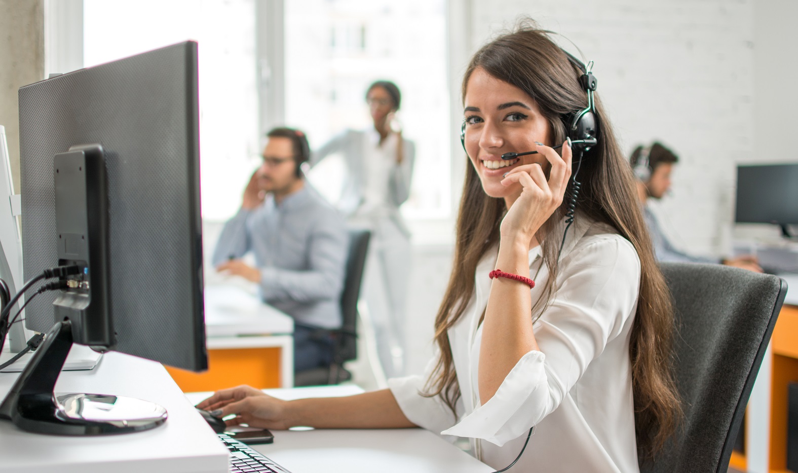 Young friendly operator woman agent with headsets working in a call centre.